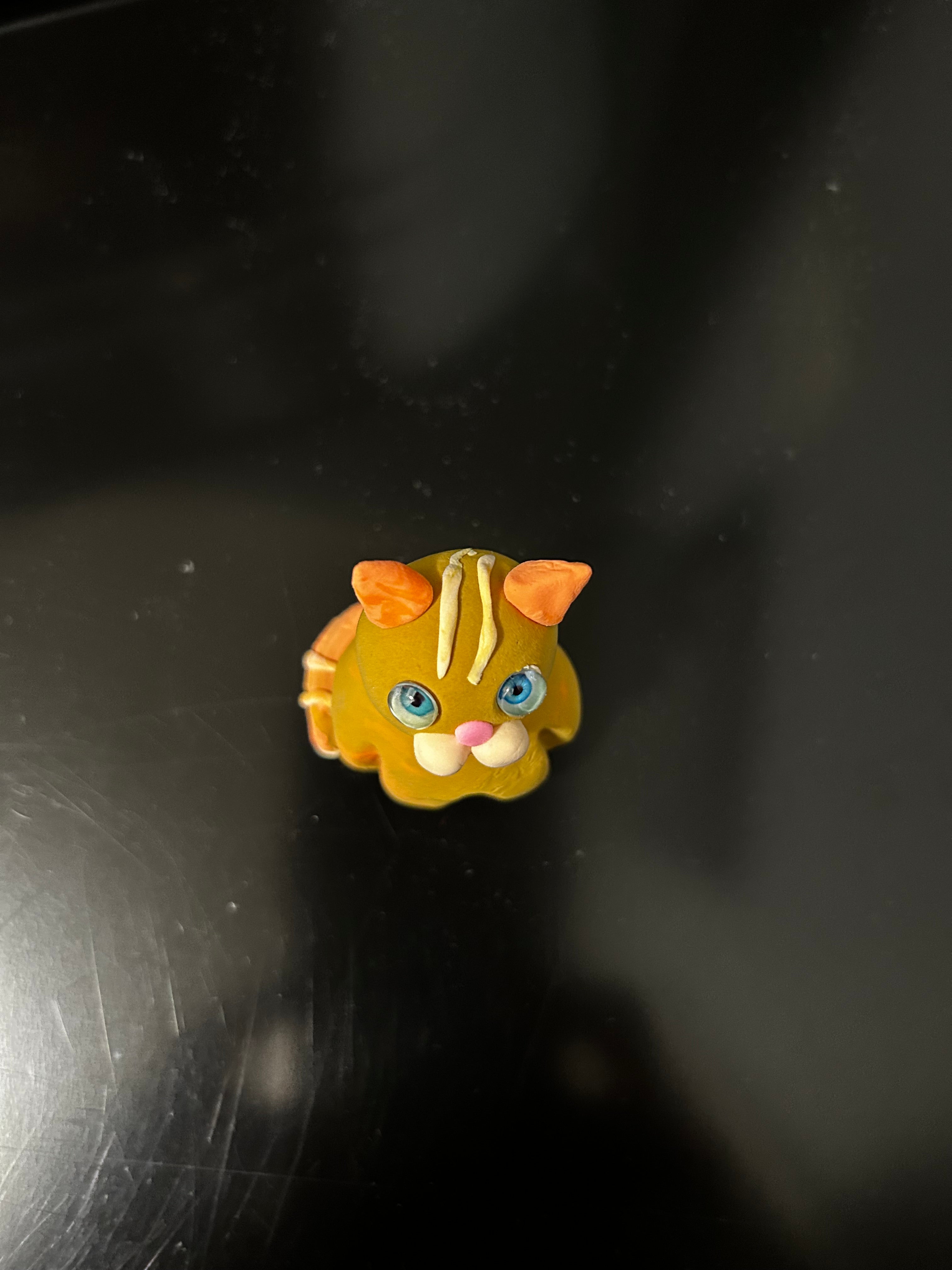 Polymer clay orange tabby cat miniature held in hand showing scale