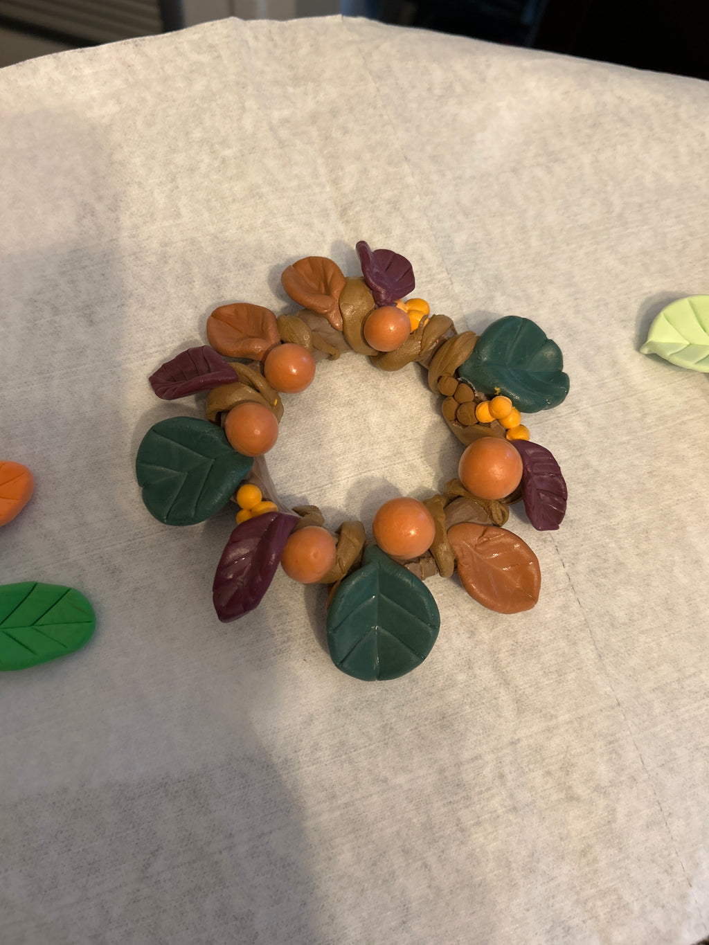 Close-up of handmade polymer clay autumn harvest wreath showing leaf and berry detail